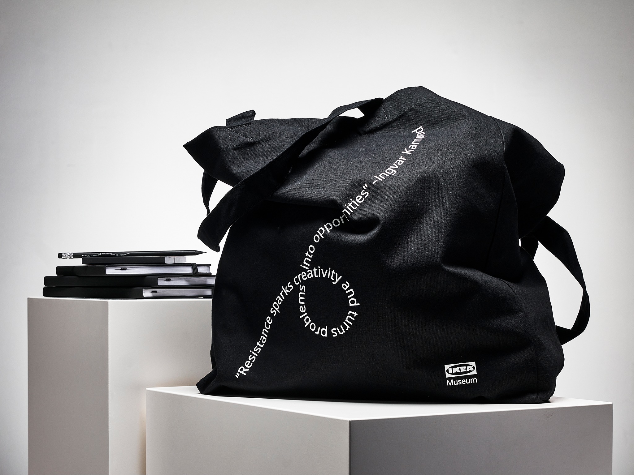 Black tote bag with white wavy text.