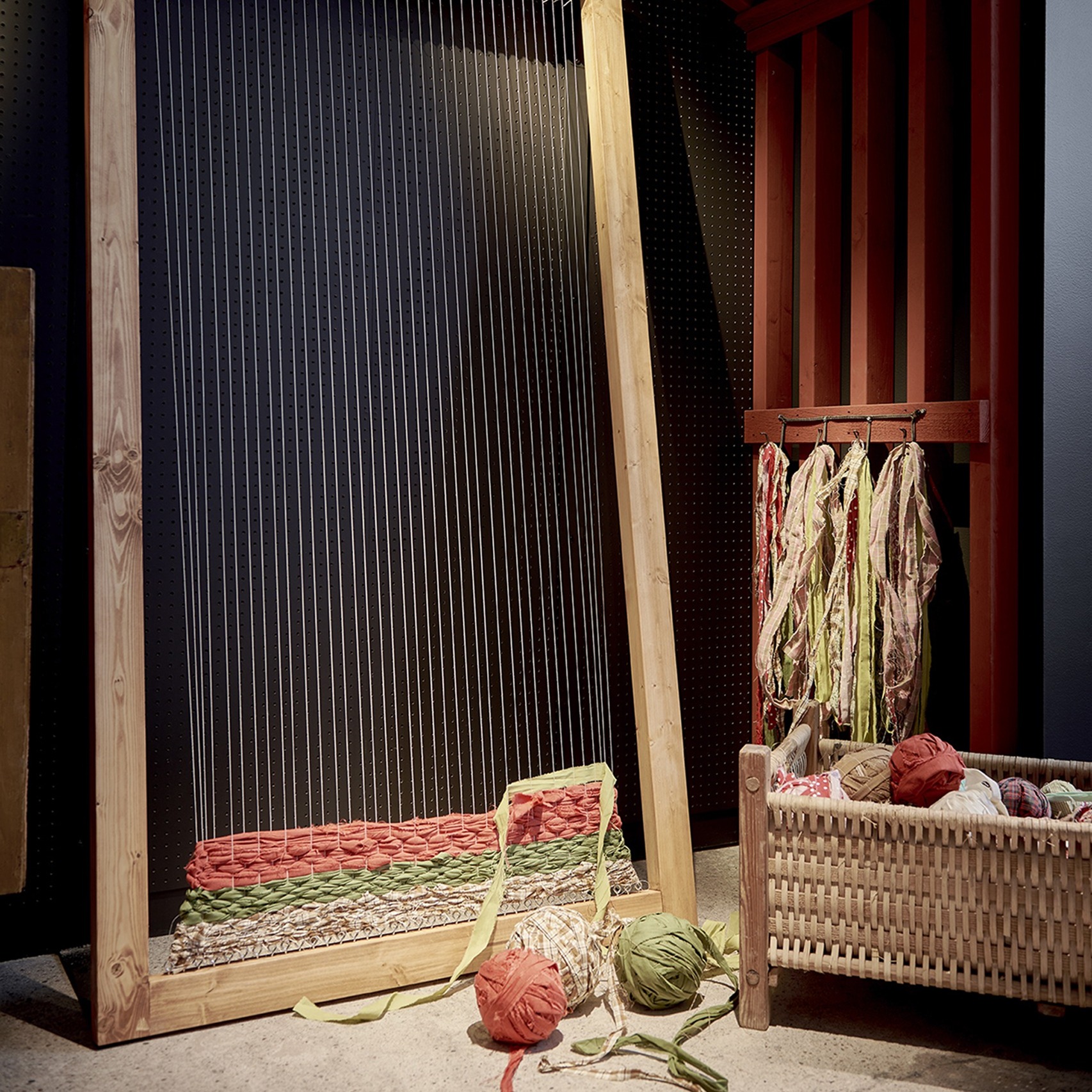 Exhibition display with a loom, woven cradle, and textiles illustrating traditional craftsmanship.